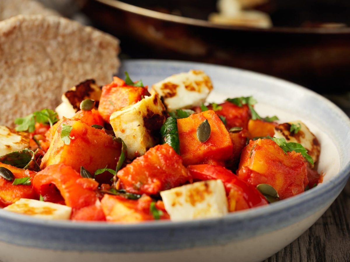 Unsere Kürbis-Halloumi-Pfanne wird in der Schale mit einem Stück Brot gereicht.