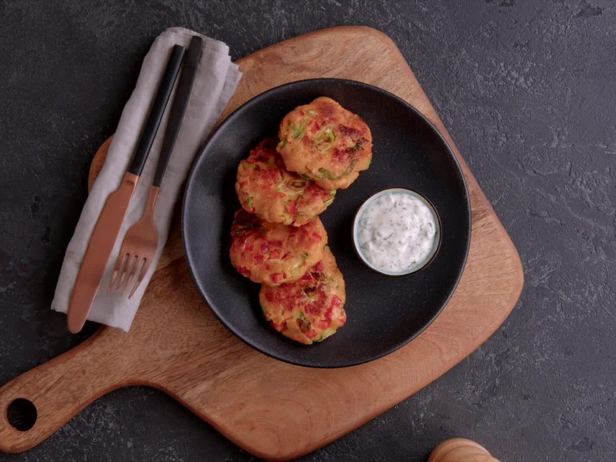 Lachs-Kroketten mit Dip auf schwarzem Teller.