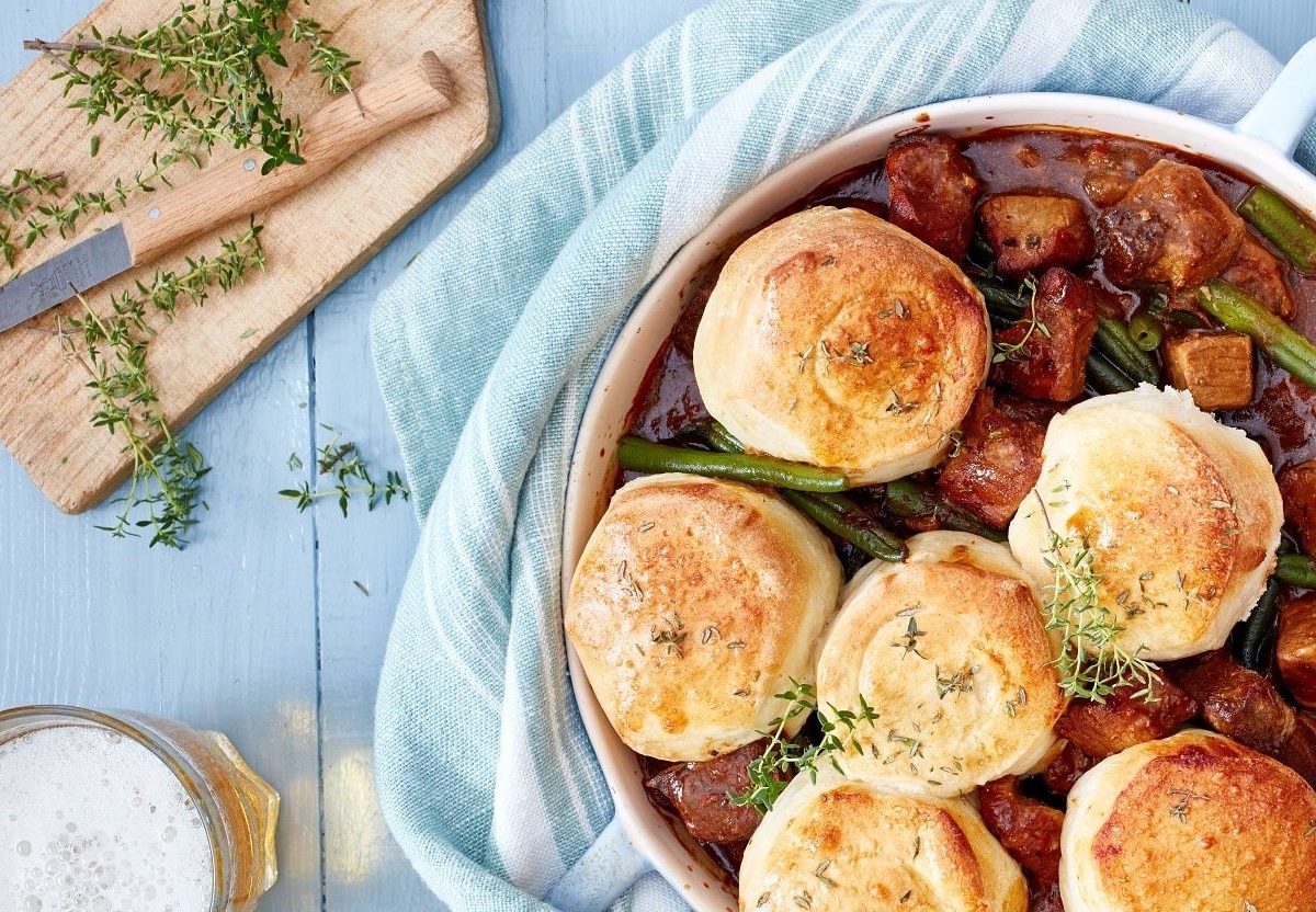 Bier-Gulasch und Brötchen gemeinsam angerichtet in einem Topf. Dazu Thymian als Deko und ein kühles Bier.