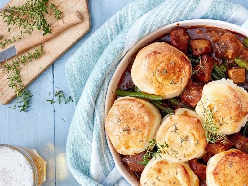 Bier-Gulasch und Brötchen gemeinsam angerichtet in einem Topf. Dazu Thymian als Deko und ein kühles Bier.