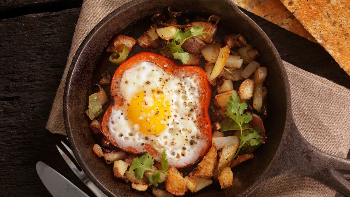 Eine Pfanne Bratkartoffeln mit Paprika-Spiegelei in der Draufsicht.