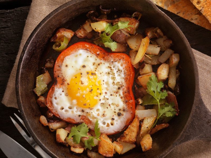 Eine Pfanne Bratkartoffeln mit Paprika-Spiegelei in der Draufsicht.