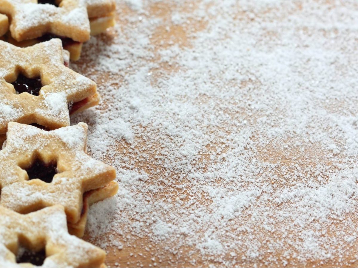 Auf einer bemehlten Arbeitsfläche sind mehrere glutenfreie Linzer Sterne.