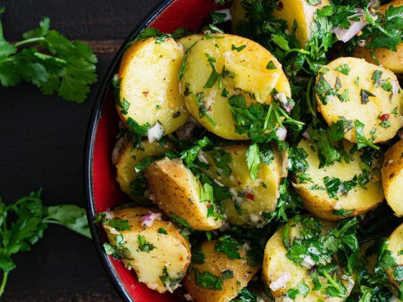 Eine Schale Kartoffelsalat mit Schalottendressing und Petersilie.