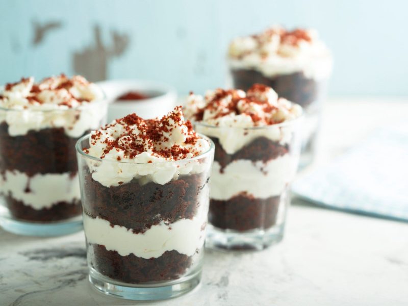 Mehrere Red Velvet Cakes im Glas auf einer Marmorplatte vor hellem Hintergrund.