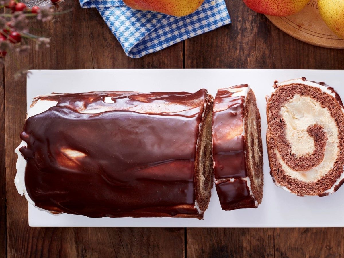 Unsere Schoko-Birnen-Rolle liegt angeschnitten auf einer Kuchenplatte.