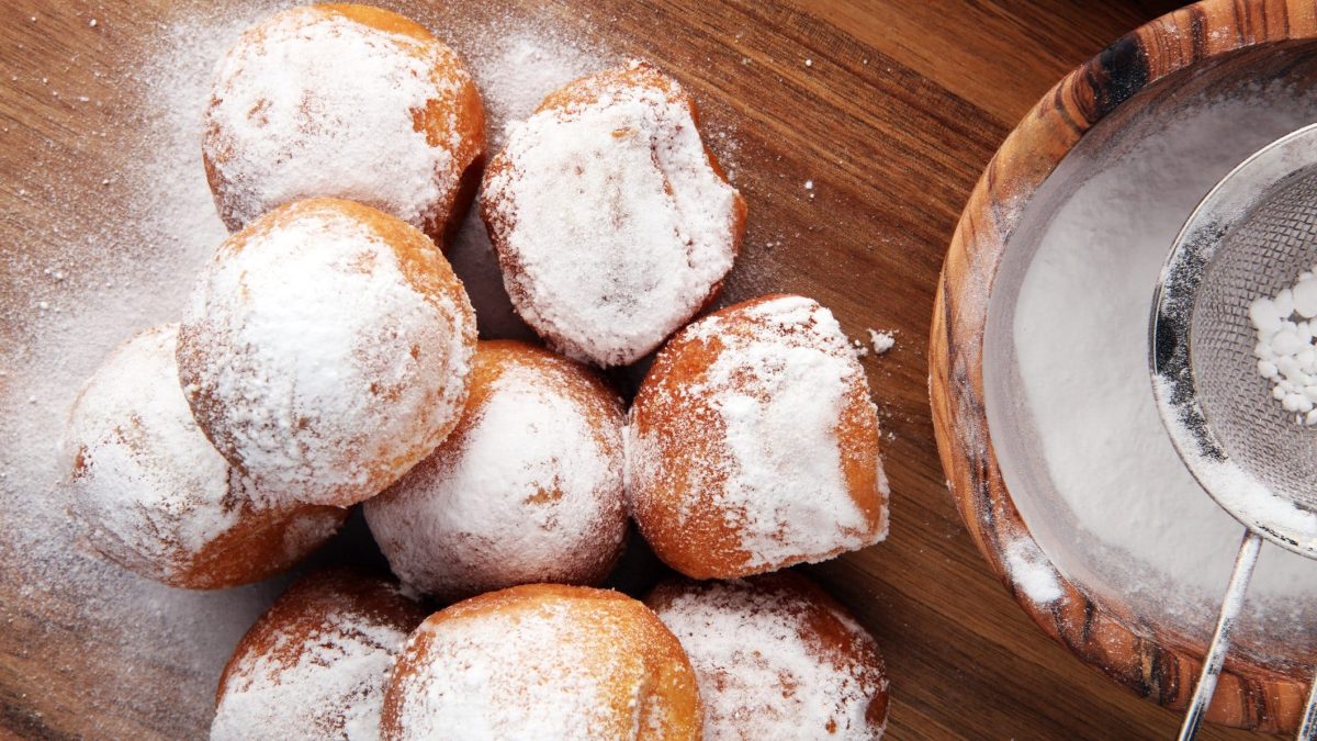 auf einer Tischplatte liegen Quarkbällchen, die mit Puderzucker bestreut sind.