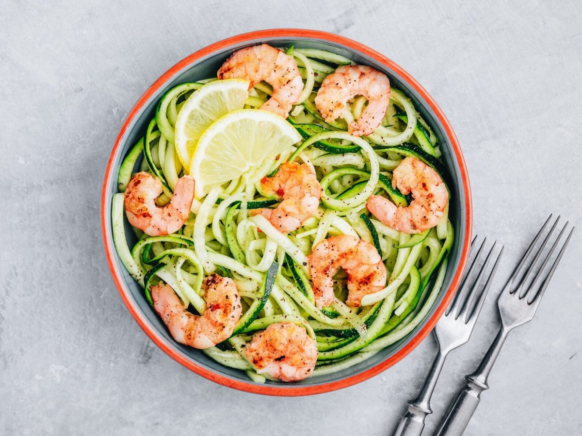 Eine Schale in der Draufsicht auf Marmoruntergrund, darin Zoodles mit Garnelen.