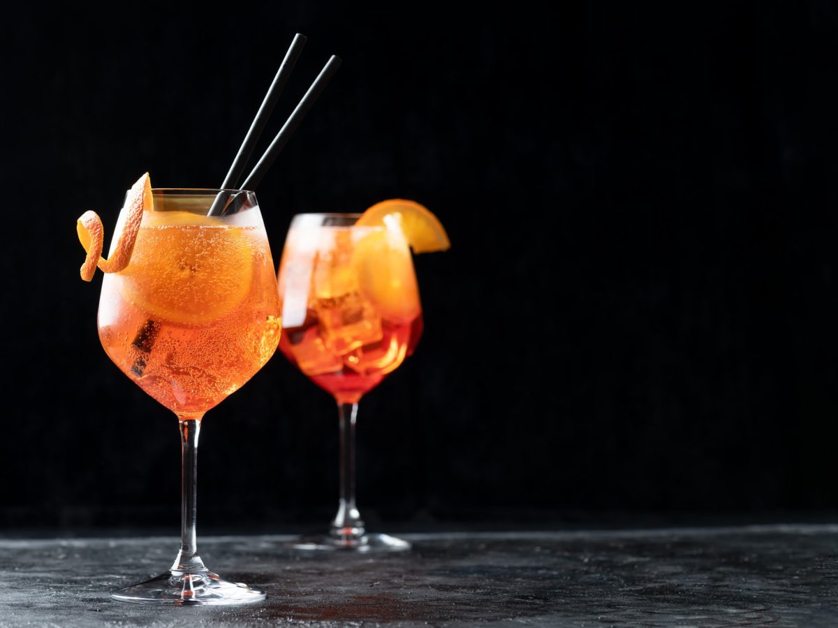 zwei Gläser mit Aperol Spritz in dunklem Ambiente