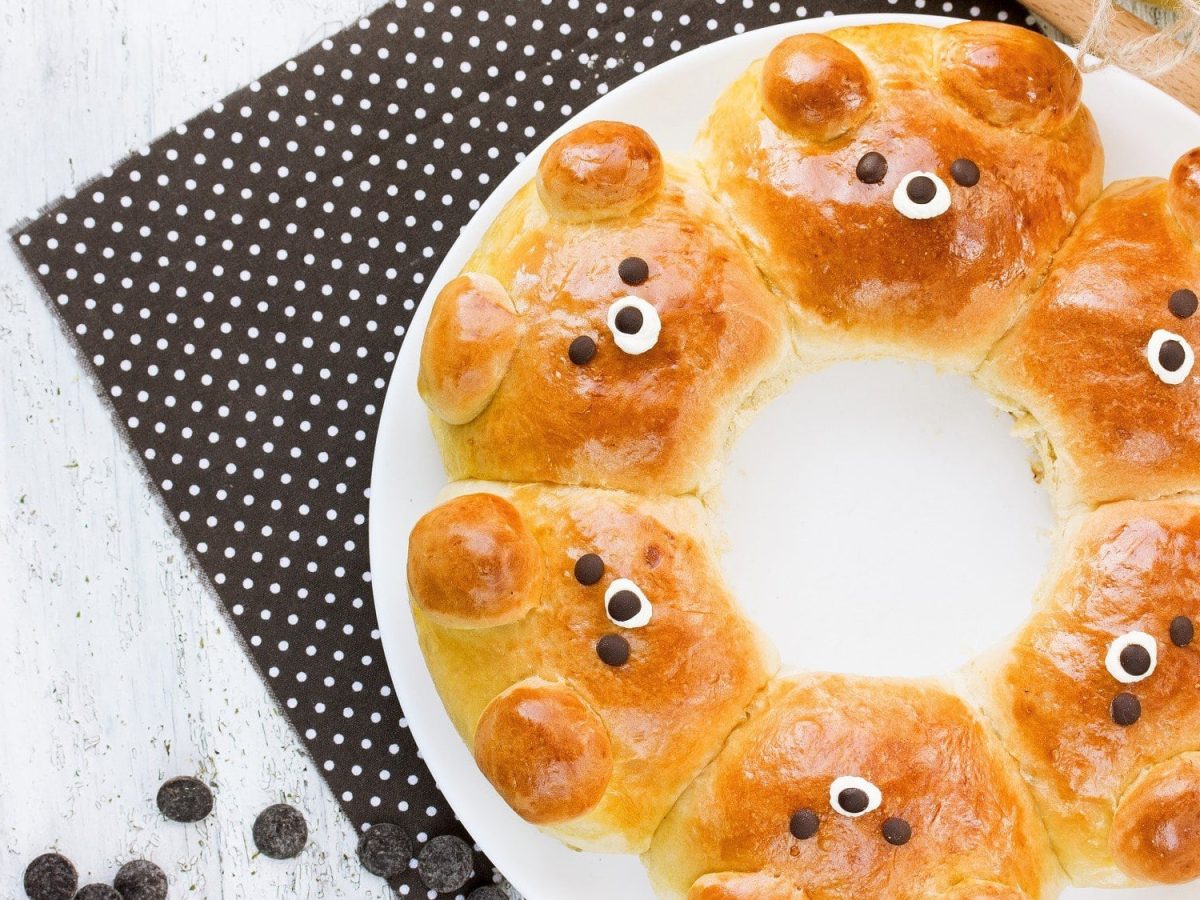 Auf einem weißen Teller liegen Bear Buns. Das Brot ist kreisförmig gebacken, in der Mitte ist ein Loch. Das Brot sieht aus wie kleine Bären.