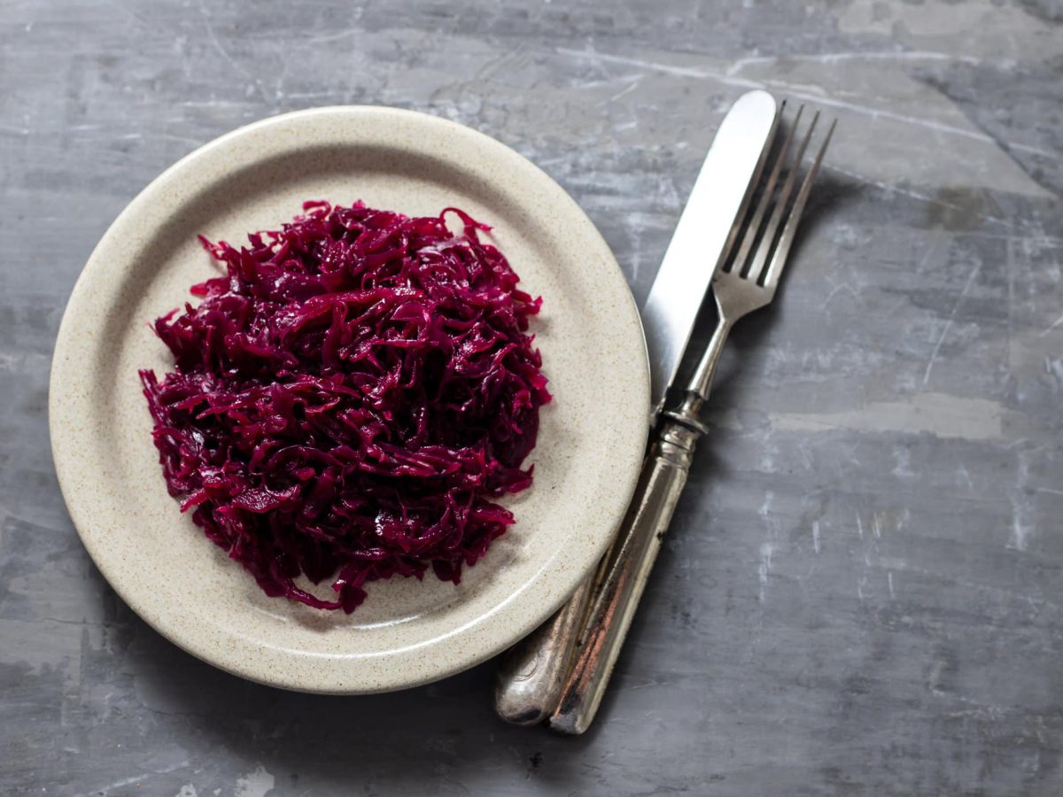 Weißer Teller mit Rotkohl auf grauem Untergrund