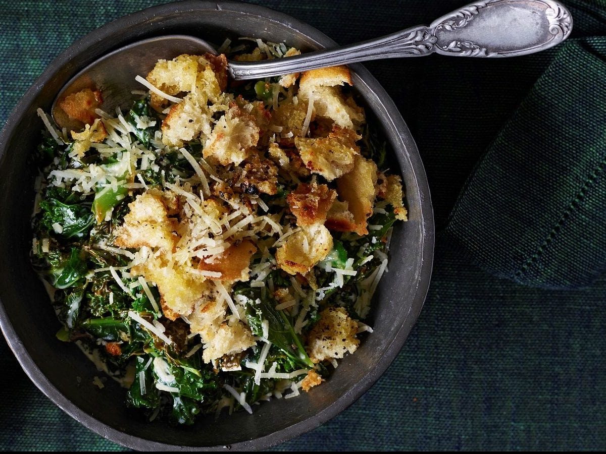 Draufsicht: Auf einem Teller ist Rahmgrünkohl mit Parmesan-Croûtons angerichtet.