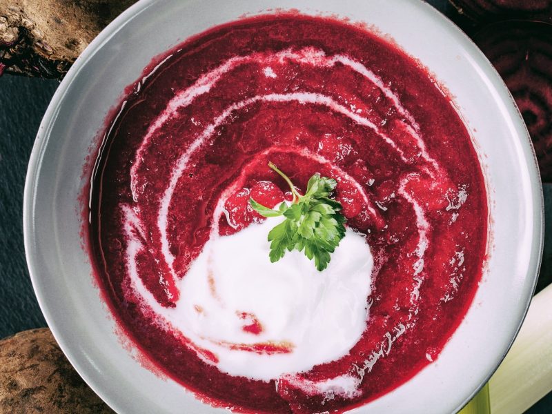 Cremige Rote Bete-Suppe mit Poree und einer Schmandhaube in einer weißen Schale serviert