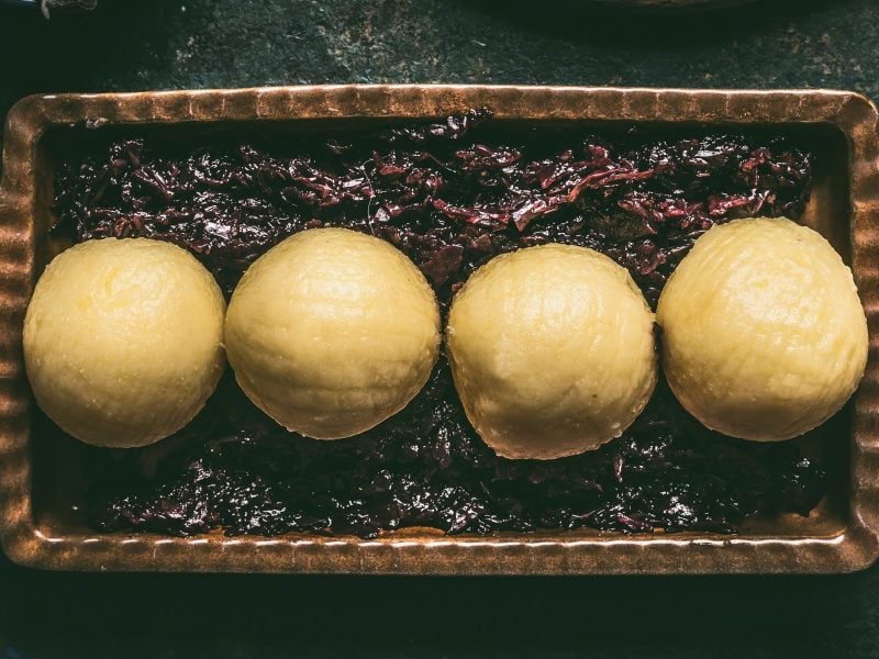 Traditionelle Kartoffelknödel in einer Form auf Rotkraut auf schwarzem Untergrund