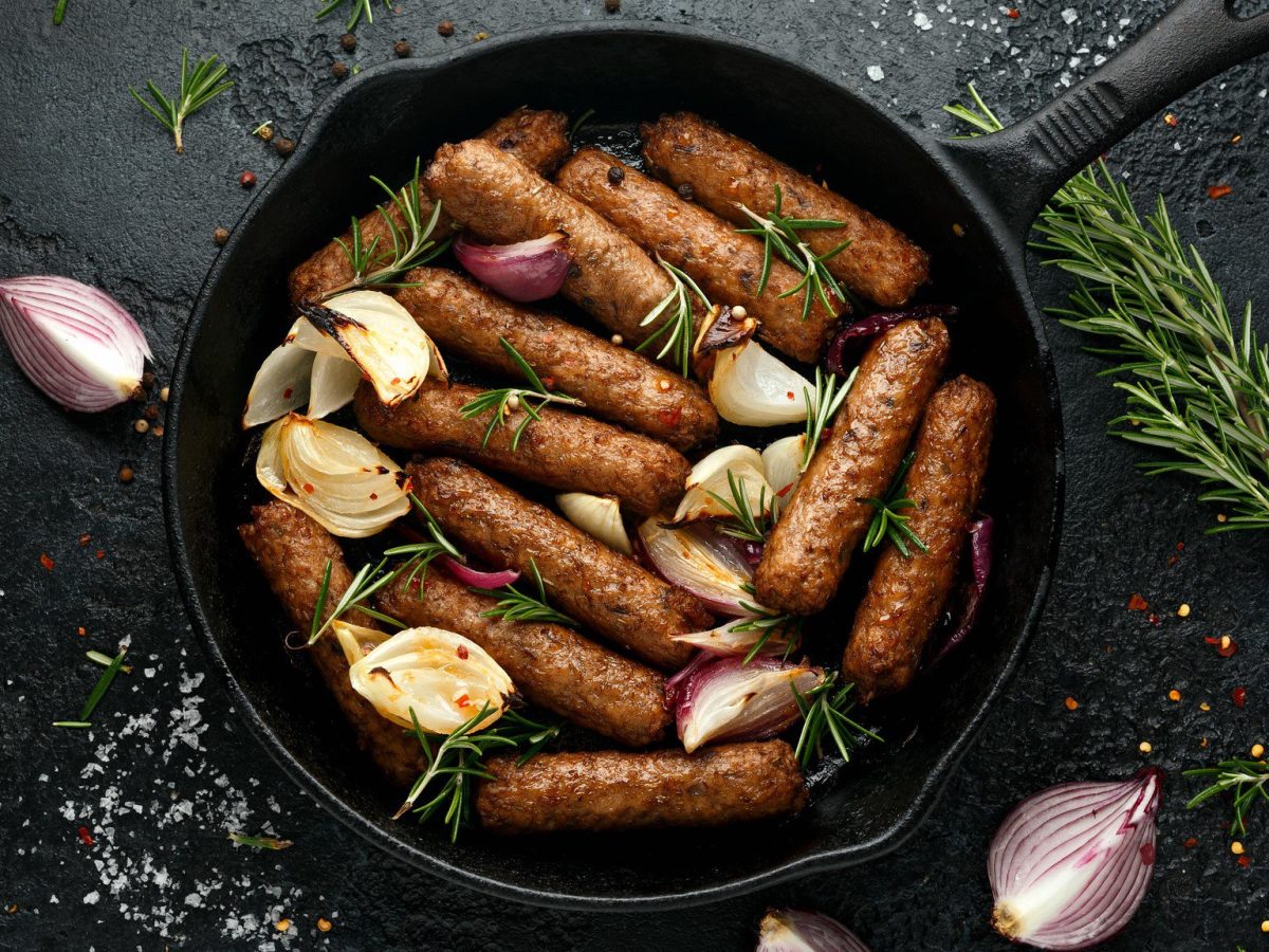 Eine Pfanne auf dunklem Schiefer in der Draufsicht, darin vegane Chorizo in Rotwein, Schalotten und Rosmarin.