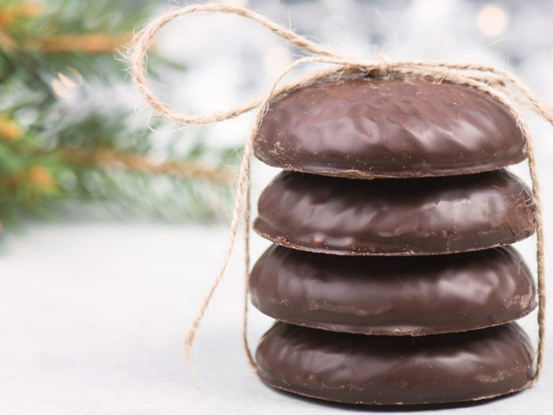 Ein Stapel vegane Elisenlebkuchen mit Band zusammengebunden vor einem hellen, unscharfen Hintergrund mit Tannenzweigen.