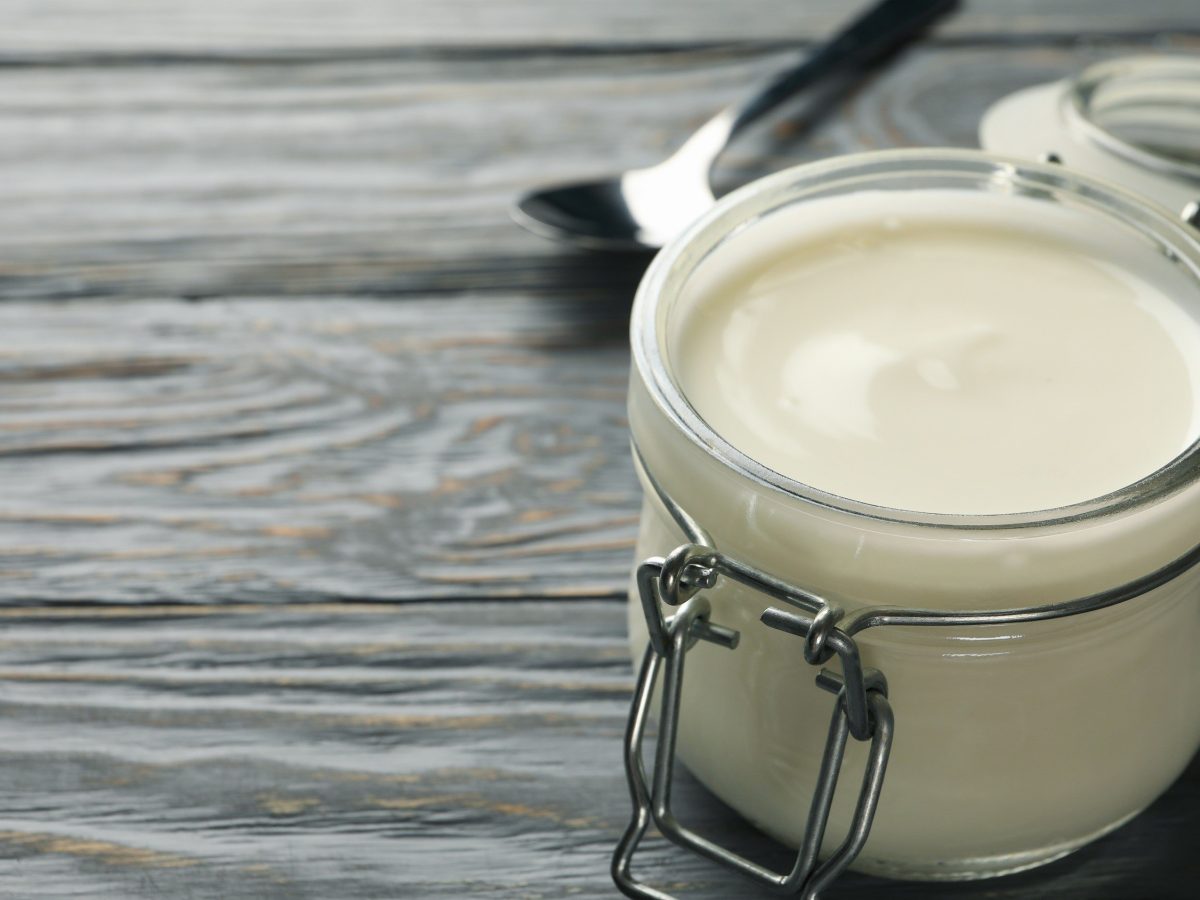 Selbstgemachte vegane Mayonnaise in einem kleinen Einmachglas auf hölzernem Untergrund