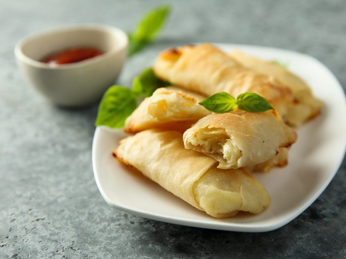 Gefüllter Börek auf weißem Teller mit einer Dip-Schale