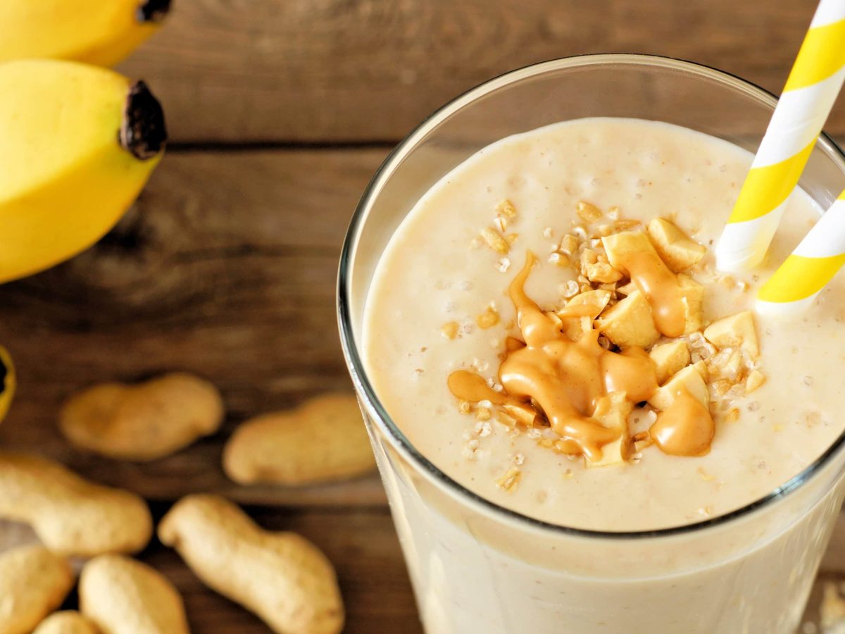 Peanutbutter-Banana-Smoothie in Glas mit zwei Strohhalmen.