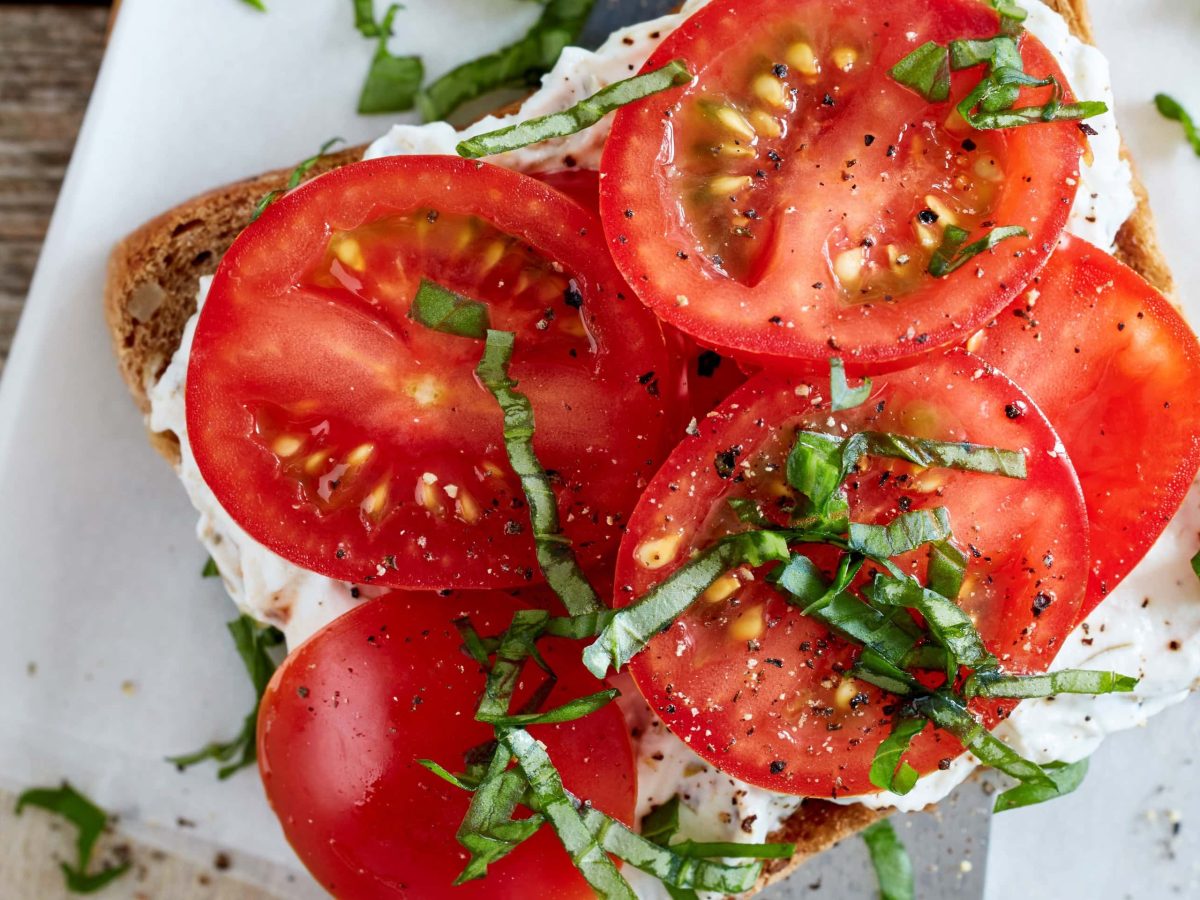 Tomaten-Sandwich mit Quark auf Brettchen serviert.