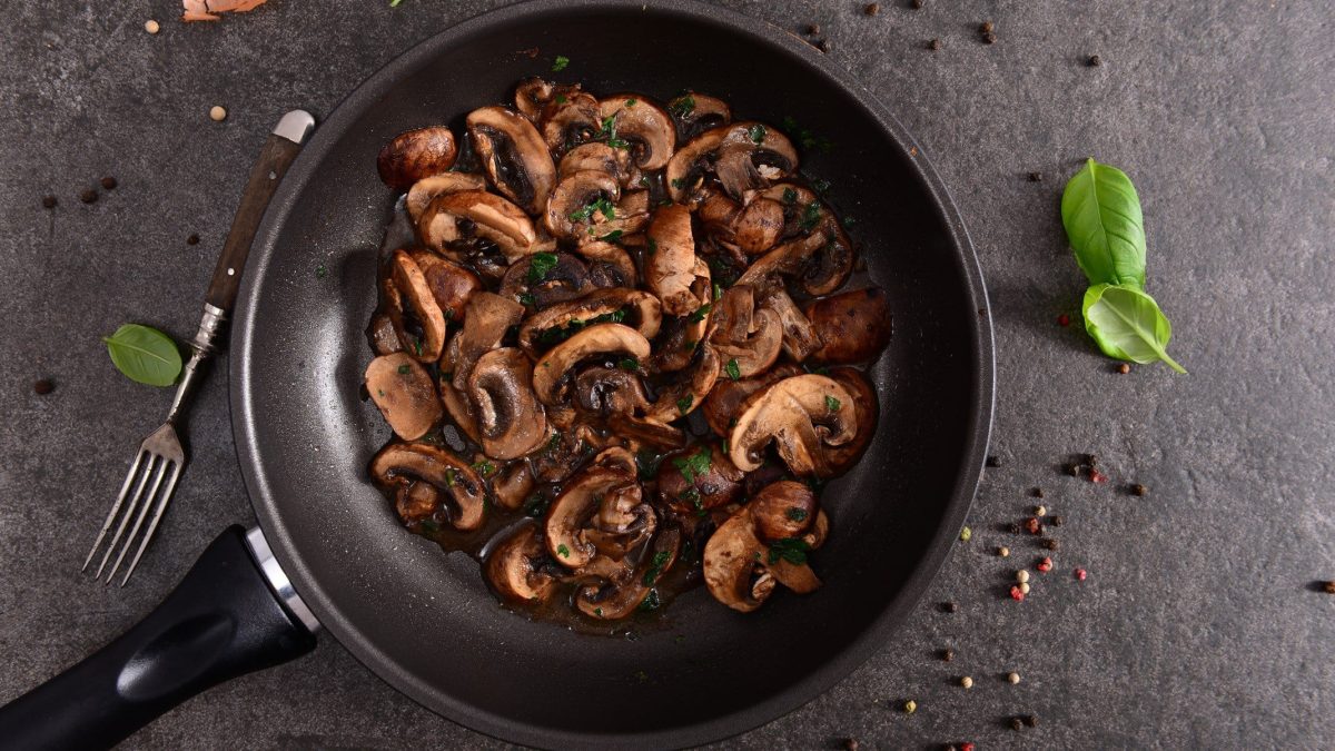 Champignons mit Kräuter-Chili-Sauce in einer Pfanne in der Draufsicht