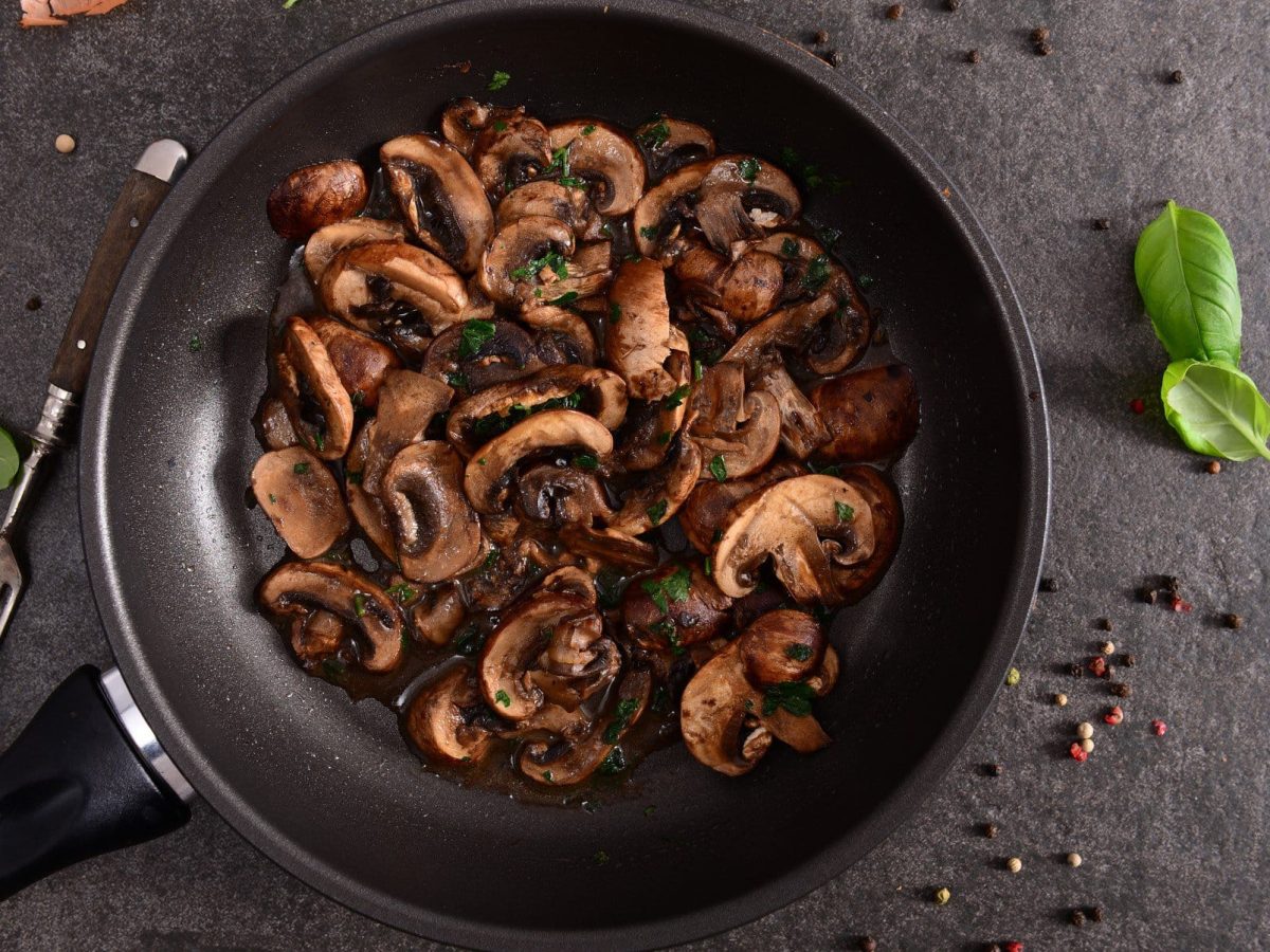 Champignons mit Kräuter-Chili-Sauce in einer Pfanne in der Draufsicht