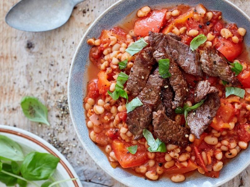 Zart gebratenes Hüftsteak in Streifen angerichtet auf einem Sud aus Baked Beans und Paprika.