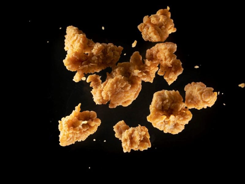 KFC Popcorn Chicken selbstgemacht und frittiert in der Luft eingefangen mit High Speed Kamera vor schwarzem Hintergrund.