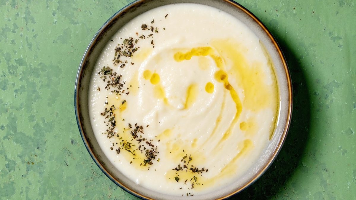 Eine Schale Pastinaken-Senf-Suppe mit getrockneten Kräutern und Öl.