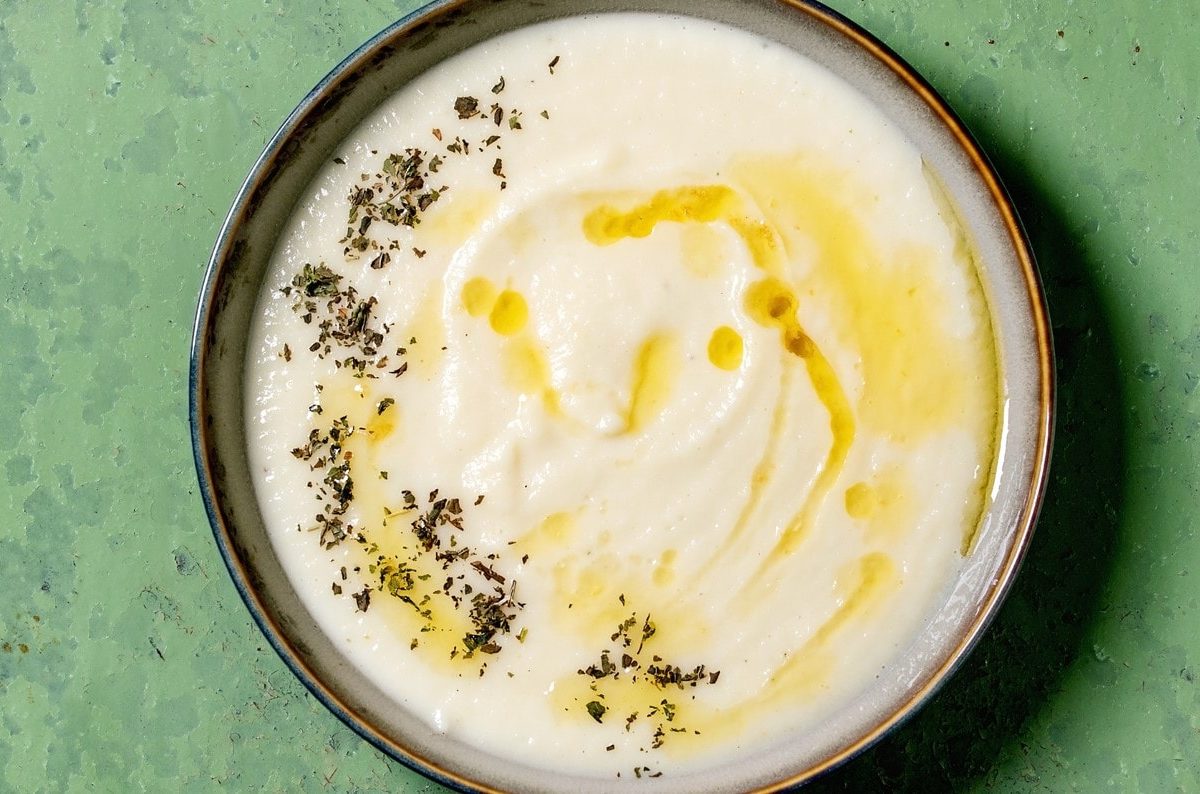 Eine Schale Pastinaken-Senf-Suppe mit getrockneten Kräutern und Öl.