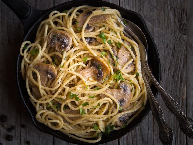 Eine Pfanne Spaghetti mit Tahinisauce, darin stecken Gabel und Löffel.