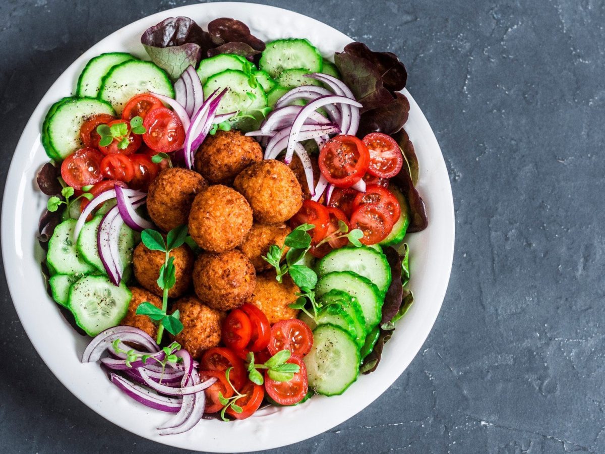 Süßkartoffel-Falafel mit Salat auf einem grauen Untergrund in der Draufsicht.