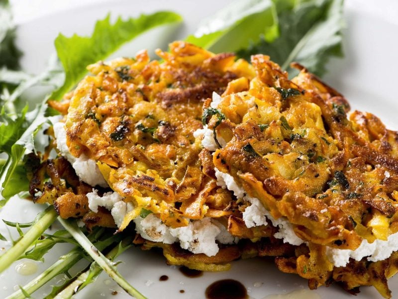 Knusprige Süßkartoffel-Fritters mit Kräutern und Ziegenkäsefüllung auf einem Salatbett aus Läwenzahn mit Balsamico und Öl