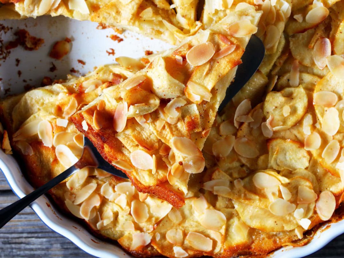 Unsichtbarer Apfelkuchen "Gâteau invisible aux pommes" in Tarteform auf hölzernem Untergrund.