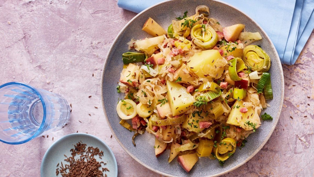 sauerkrautpfanne mit kartoffeln von oben mit rosa tisch und hellblauer deko