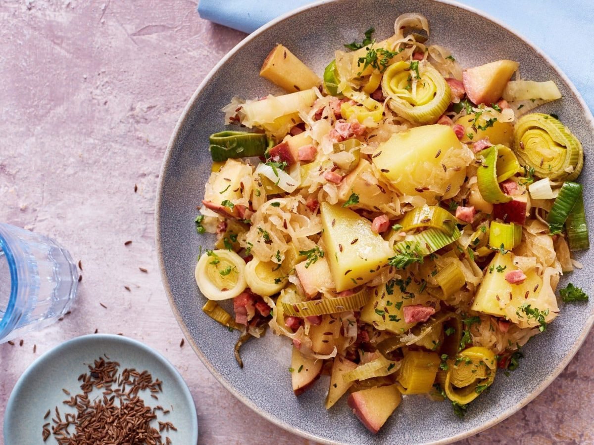 sauerkrautpfanne mit kartoffeln von oben mit rosa tisch und hellblauer deko