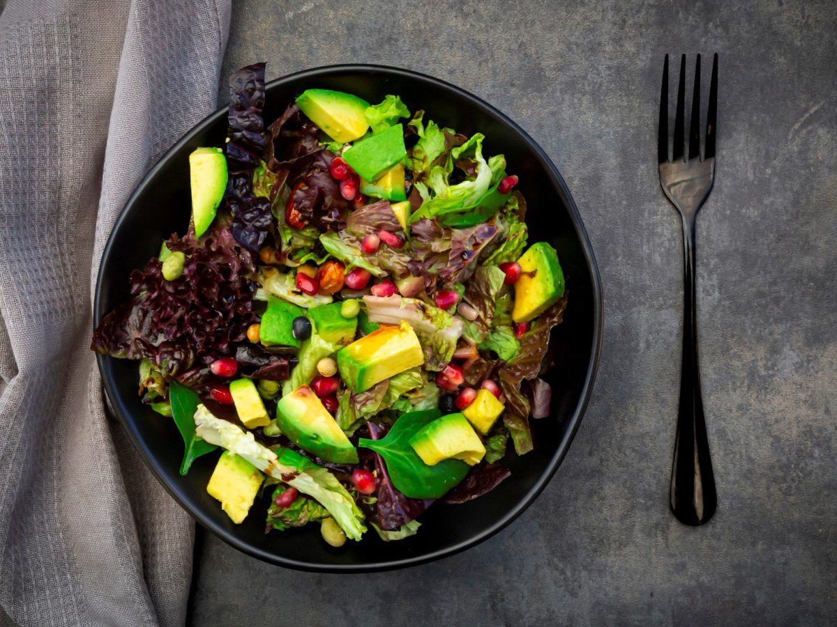 Avocado-Salat mit Granatapfel auf Teller angerichtet.