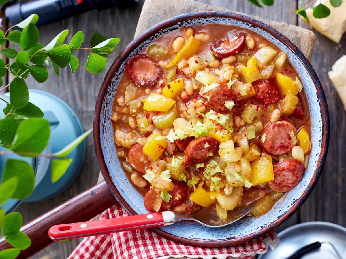 Baked Beans Pfanne von oben mit Petersilie Tuch und Baguette im Hintergrund