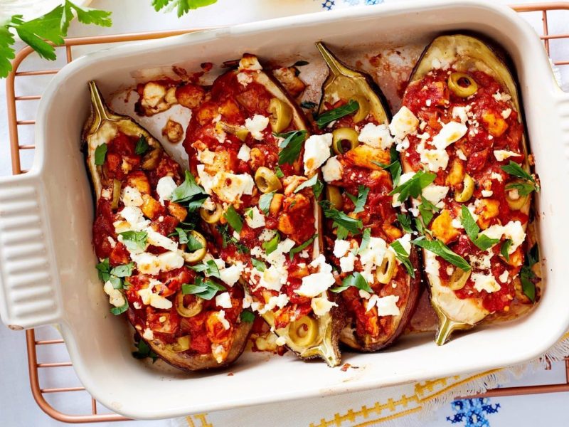 In einer Auflaufform sind vier griechische Auberginen mit Huhn gebacken. Sie sind mit Feta und Petersilie bestreut.