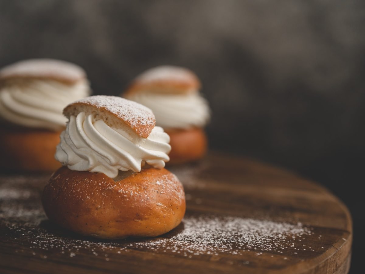 Drei Schwedische Semlor auf Holzbrett und dunklem Hintergrund