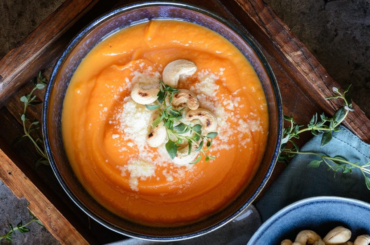 Unsere Süßkartoffelsuppe mit Pecorino und Cashews auf einem Tablett angerichtet.