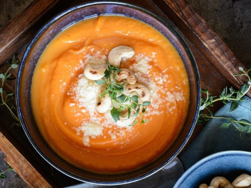 Unsere Süßkartoffelsuppe mit Pecorino und Cashews auf einem Tablett angerichtet.