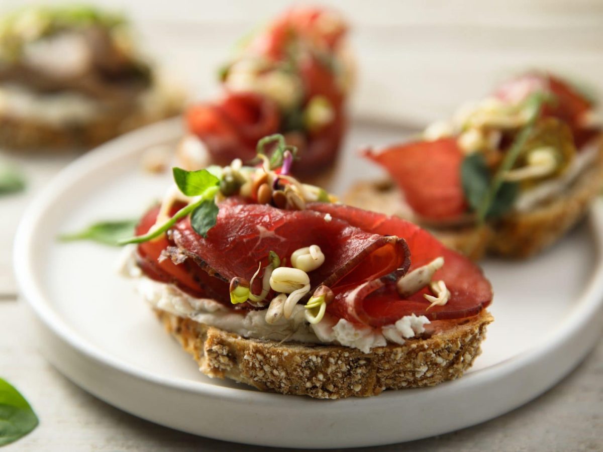 Das Carpaccio-Bruschetta liegt auf einem runden weißen Teller.