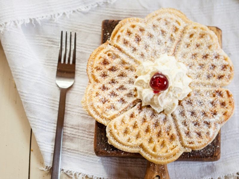 Mit Puderzucker bestäubte Waffeln auf Holzbrett