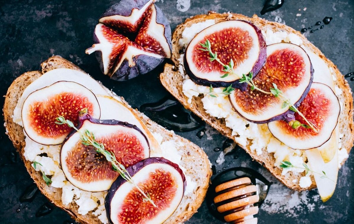 Zwei Scheiben Feigen-Ziegenkäse-Brot liegen auf einer schwarzen Schiefertafel.