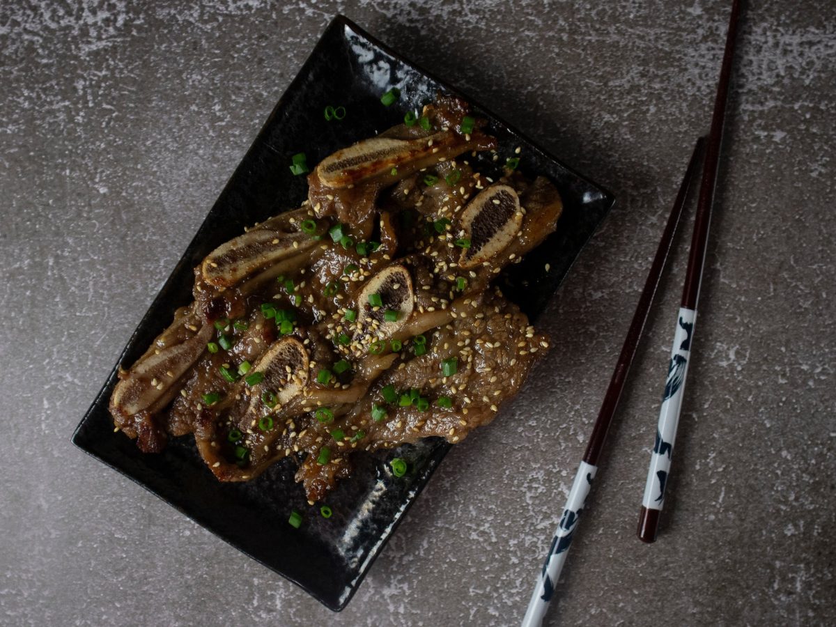 aufnahme von galbi von oben auf eckigem teller mit stäbhcen auf grauem tisch