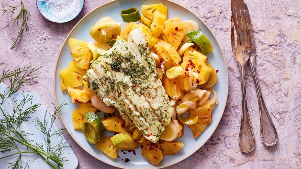 Ein Teller voll mit süß-saurem Ananas-Ragout mit Kabeljau steht auf dem Tisch.