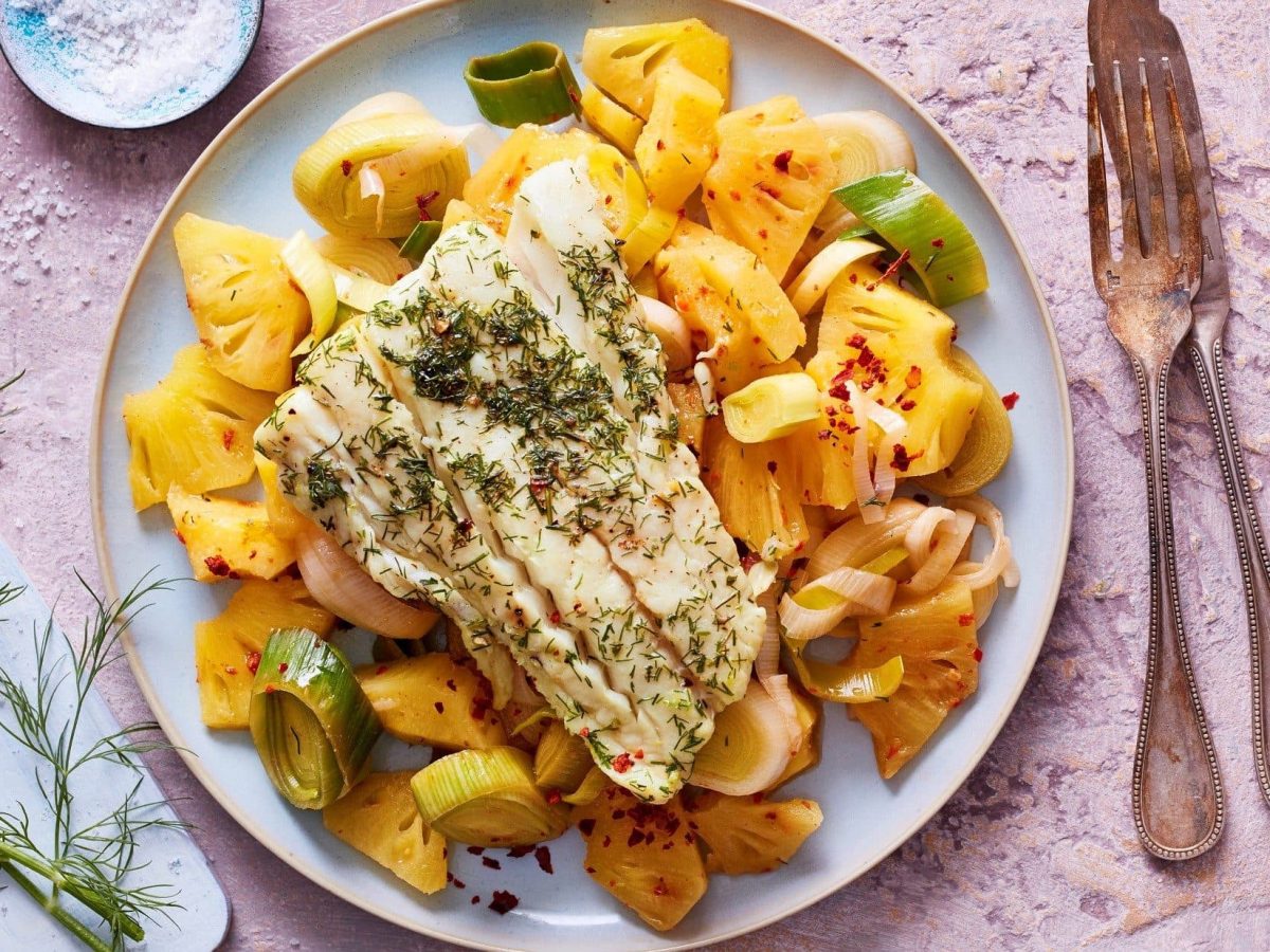 Ein Teller voll mit süß-saurem Ananas-Ragout mit Kabeljau steht auf dem Tisch.