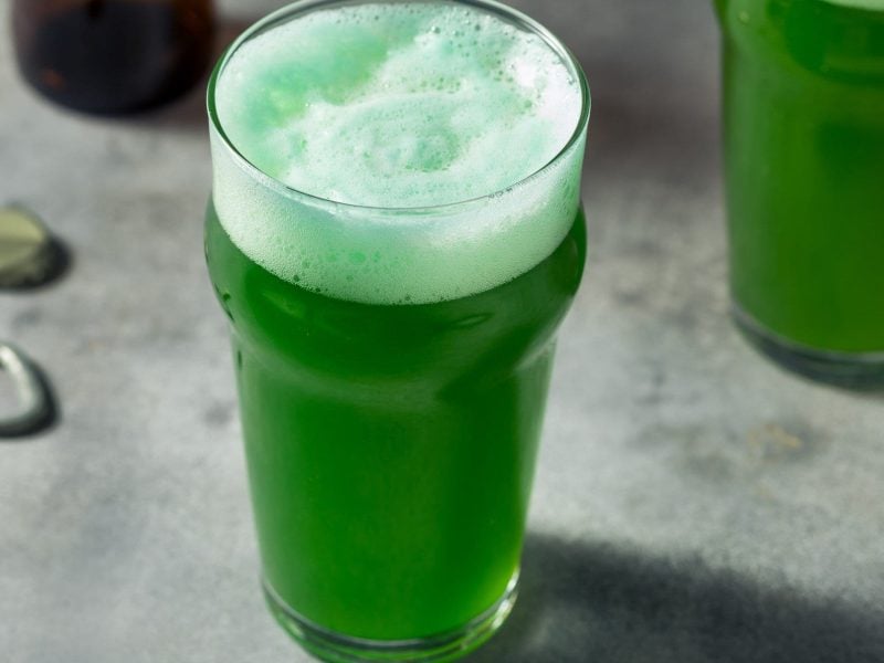 Zwei Gläser Green Beer auf einem grauen Untergrund.