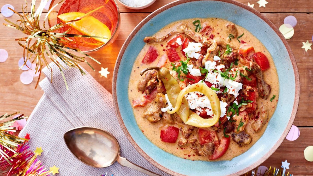 Gyrossuppe mit knackiger Paprika in einer blauen Schale. Daneben Cocktails und Party-Dekoration